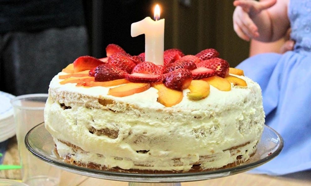 Child's hand pointing toward a birthday cake with a "Number 1" candle.