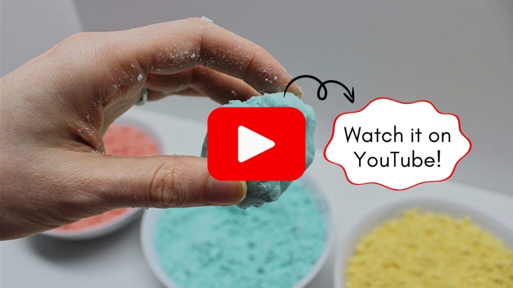 Image of a hand holding up a ball of blue sand, with a button for watching the video on YouTube.