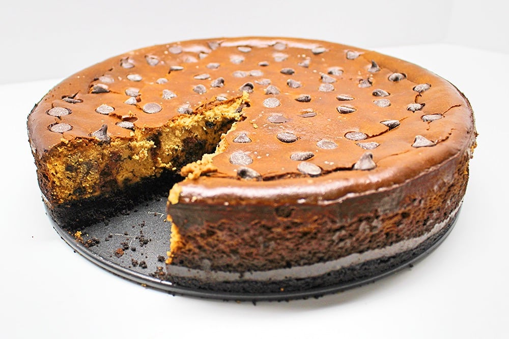 Chocolate chip cheesecake with a slice cut out.