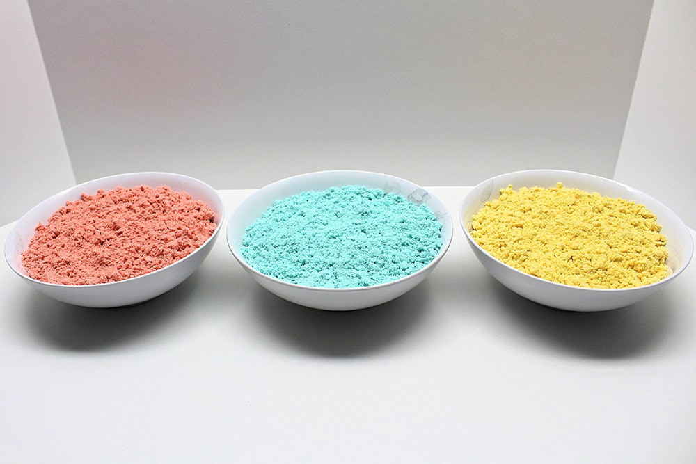 3 bowls containing red, blue and yellow moon sand.