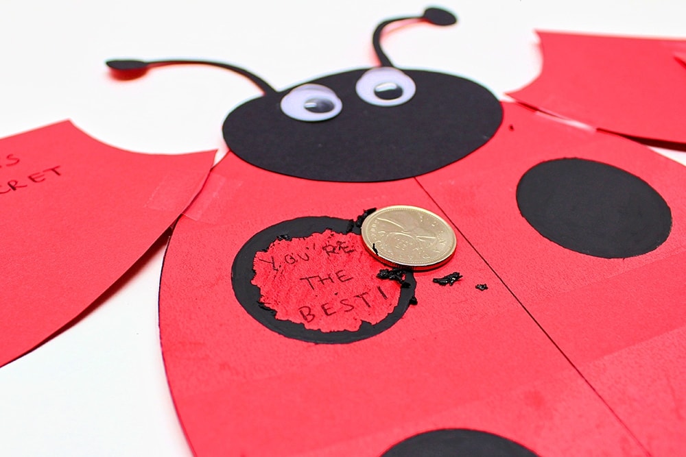Ladybug card with one dot scratched off the reveal the words "You're the best!".