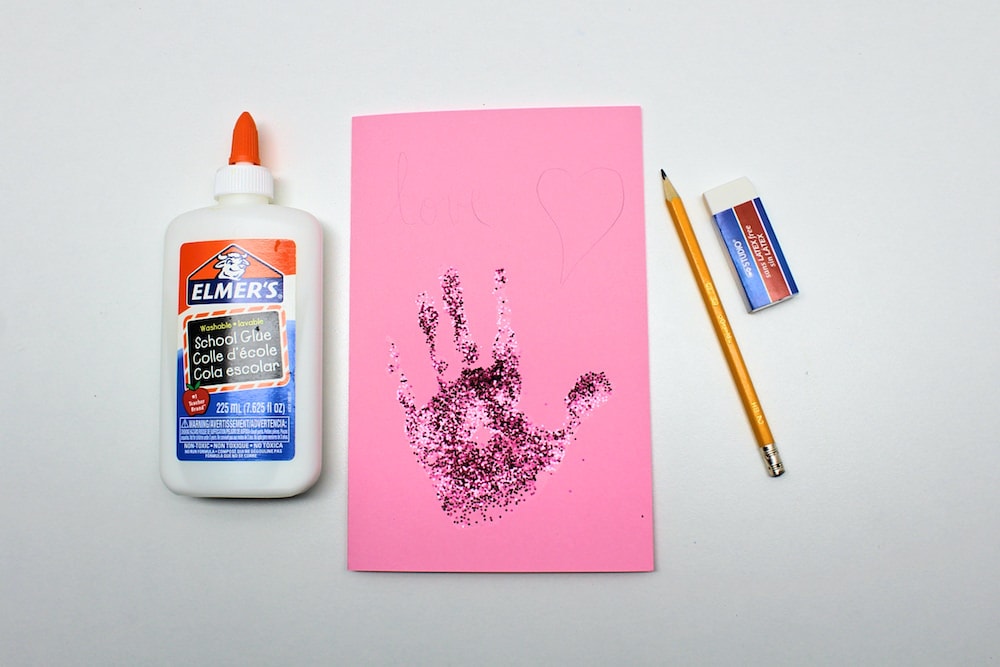 Glitter handprint card with light embellishments traced with pencil.