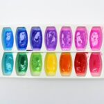 White ice cube tray containing a rainbow array of bath paint colours.