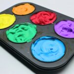 Muffin tin filled with colourful shaving cream paint.