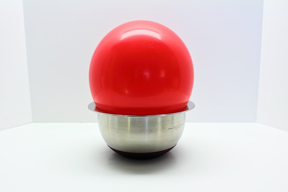 Red balloon in metal bowl.