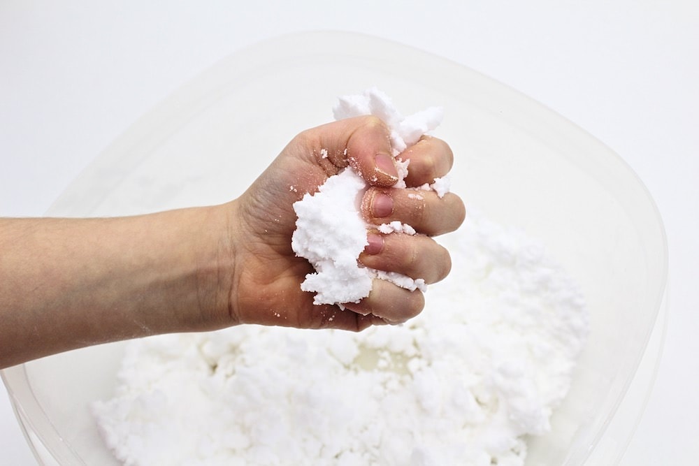 Child's hand holding a fistful of white play snow.