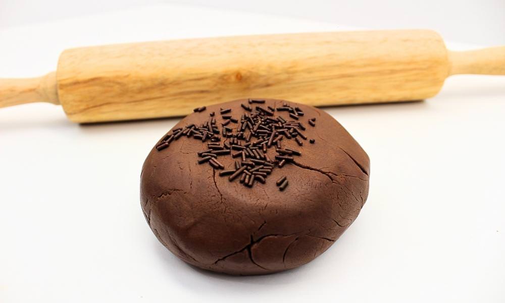 Ball of edible chocolate play dough with chocolate sprinkles in front of rolling pin