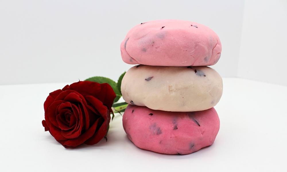 Stack of 3 balls of rose petal play dough beside a red rose