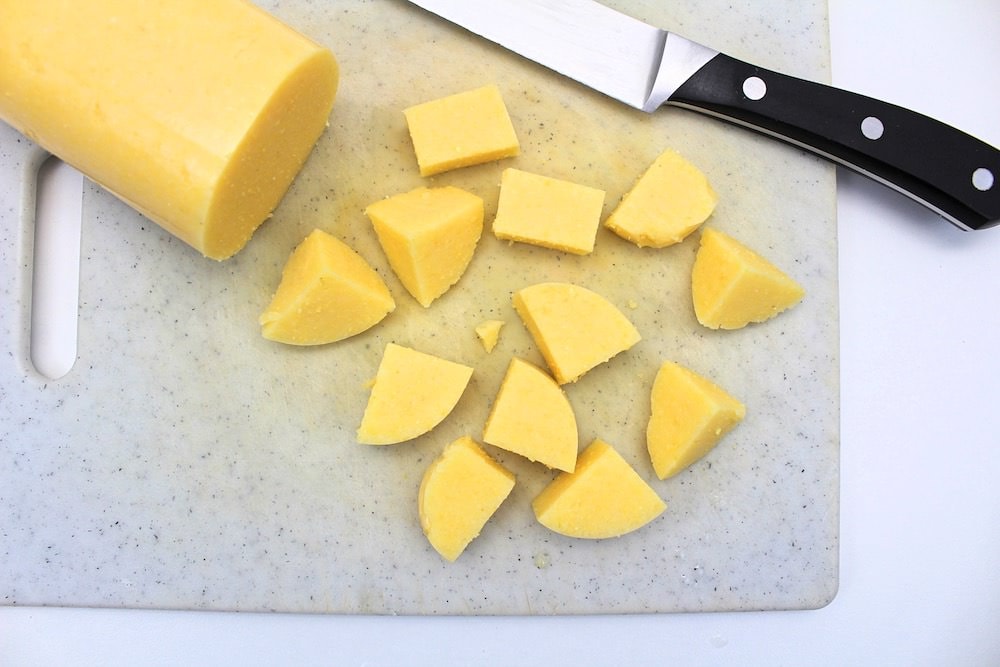 Cubes of polenta on cutting board with knife.