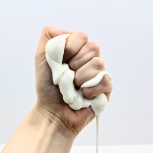 Hand squishing white dish soap silly putty