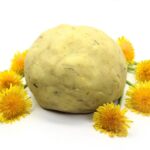Dandelion play dough surrounded by dandelion flowers.