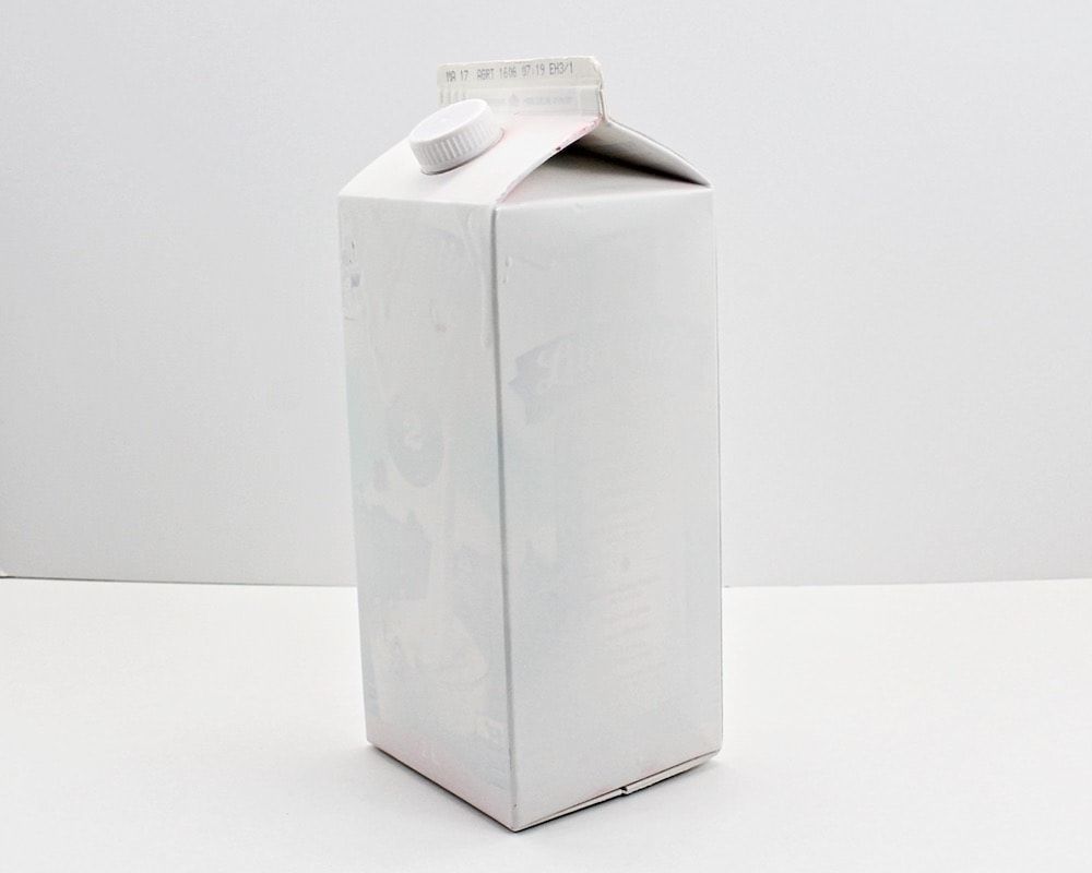 Milk carton covered with white spray paint.