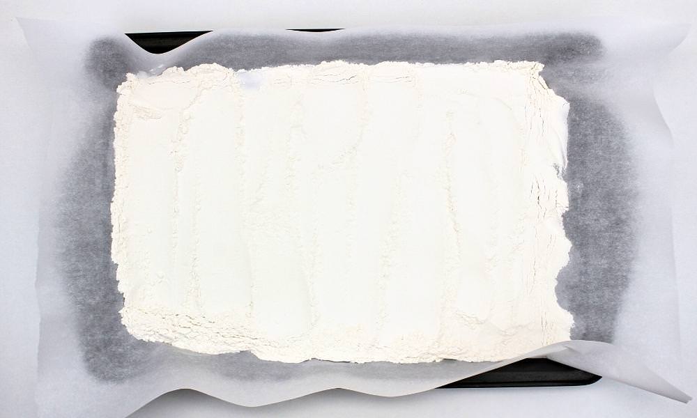 All-purpose flour spread out on a baking sheet covered with parchment paper