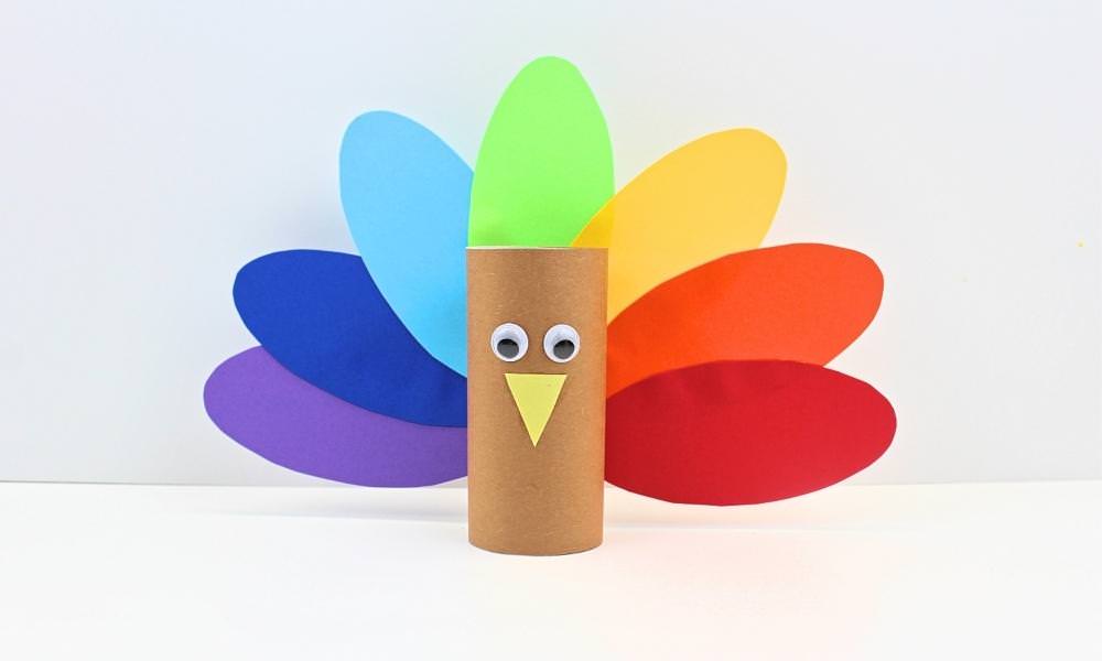 Colourful toilet paper roll turkey craft with rainbow feathers.
