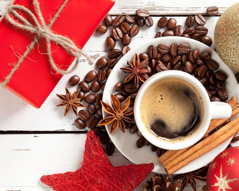 Coffee cup laid out in a pretty way for Christmas with red gift box, coffee beans and star anise.