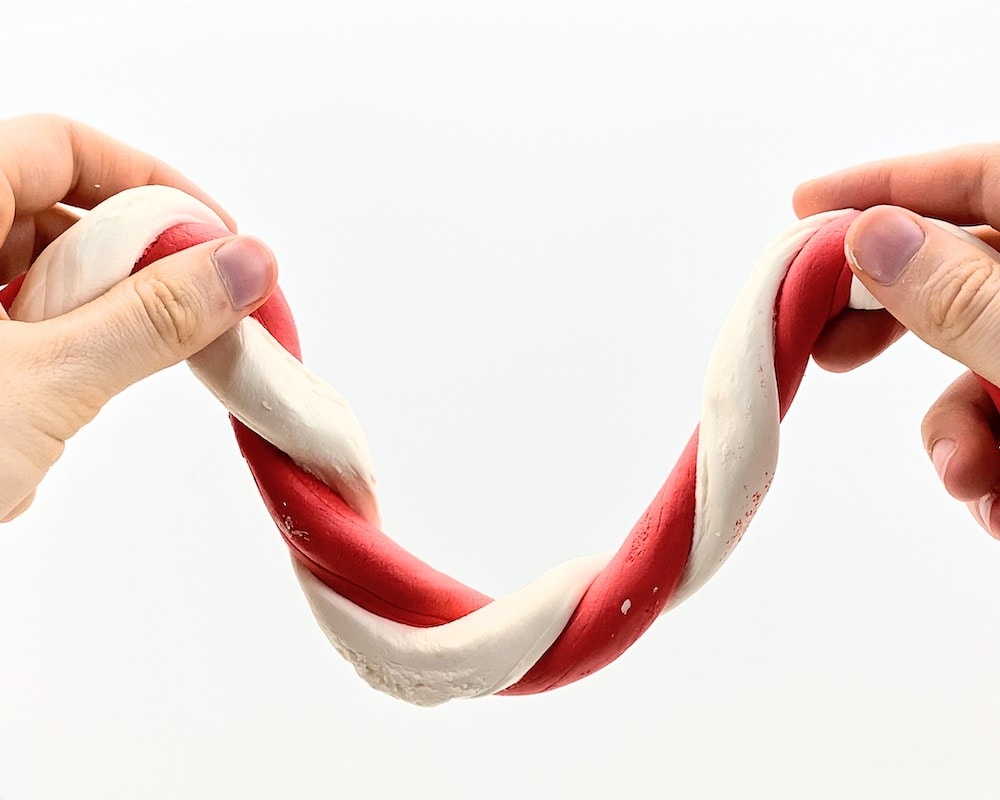 Hands holding stretchy candy cane slime.