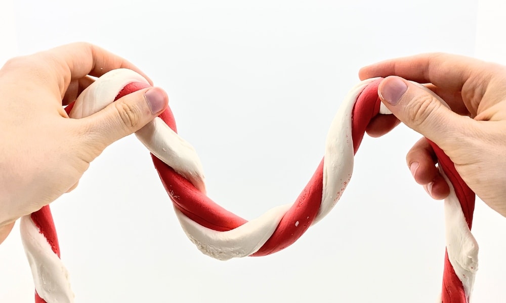 Hands holding stretchy candy cane slime