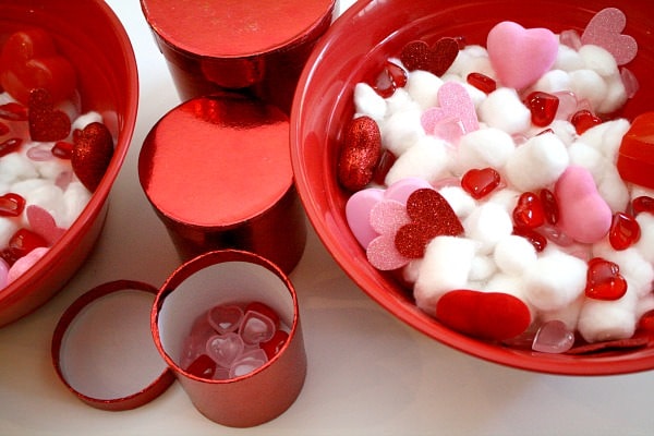 Bowl filled with cotton balls and plastic hearts.