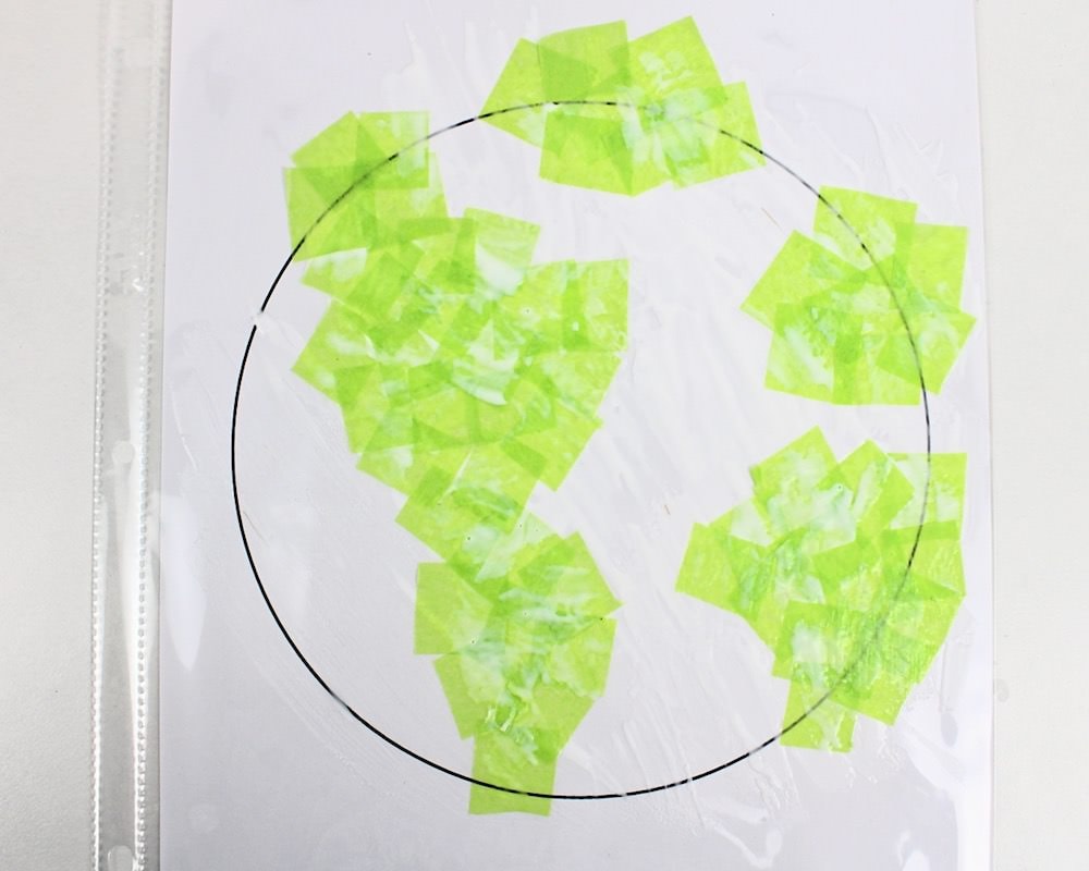 Circle template with green tissue paper arranged into the shape of continents.