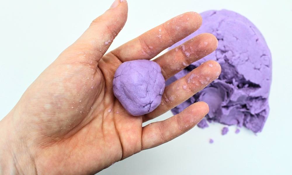 Hand holding up a ball of taste-safe kinetic sand