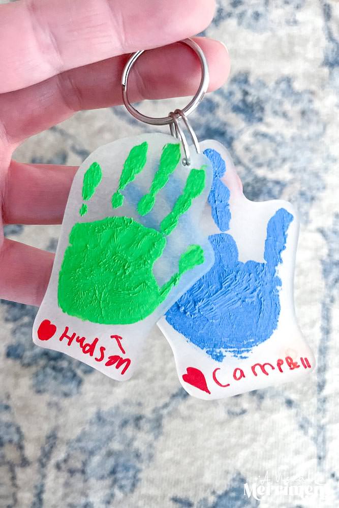 Hand holding up two handprint keychains.