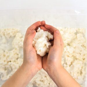 Child's hands holding a ball of white dough.