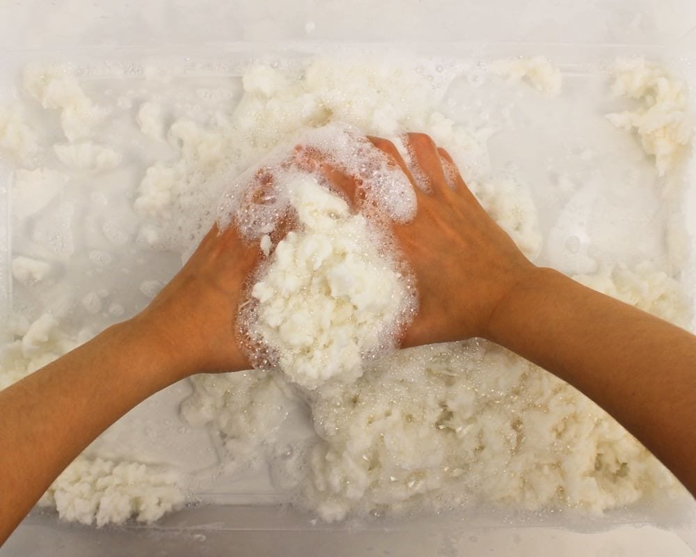 Child's hands moulding soapy white dough.