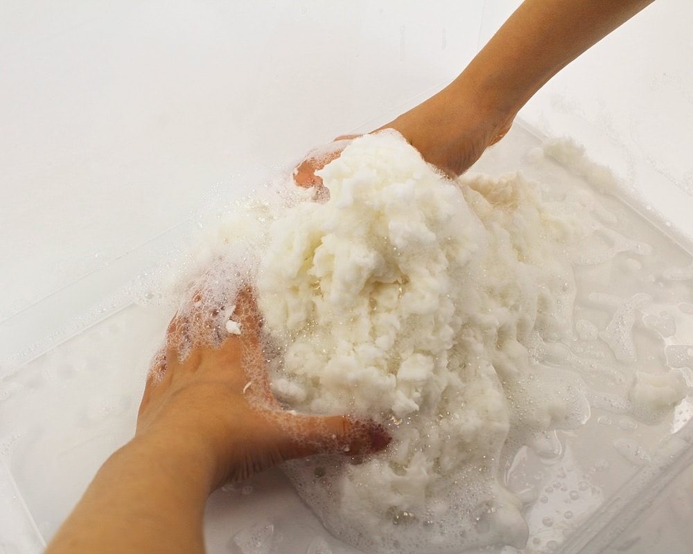 Child's hands moulding soapy white dough.