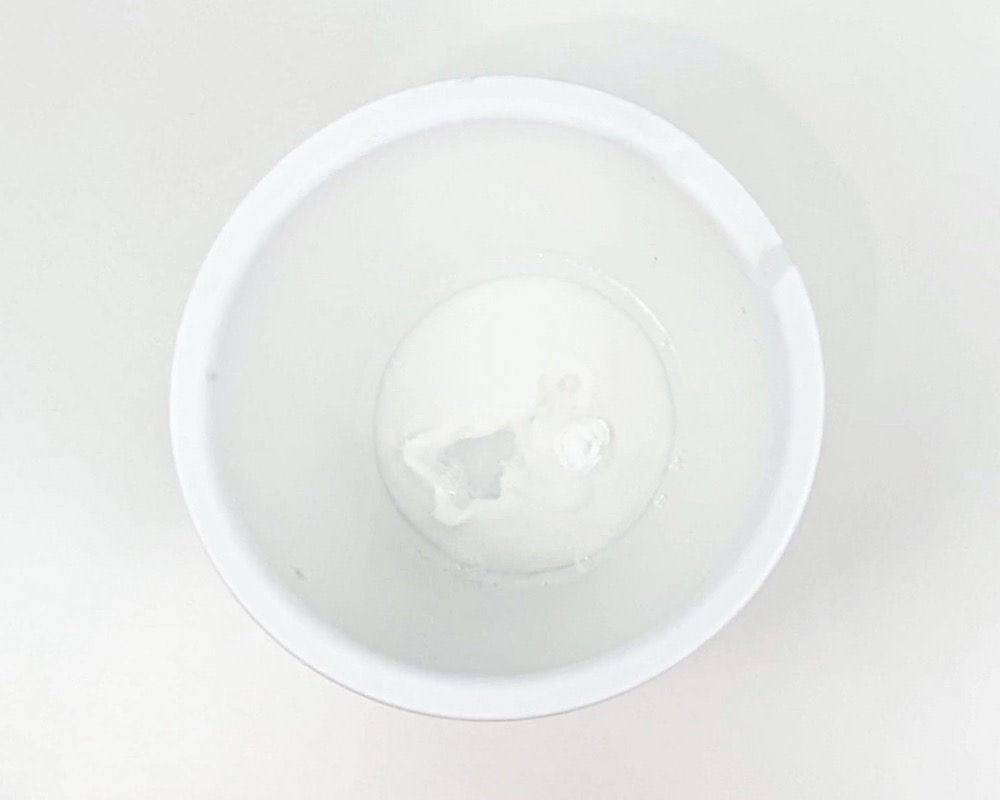White bowl with white glue, water and baking soda.