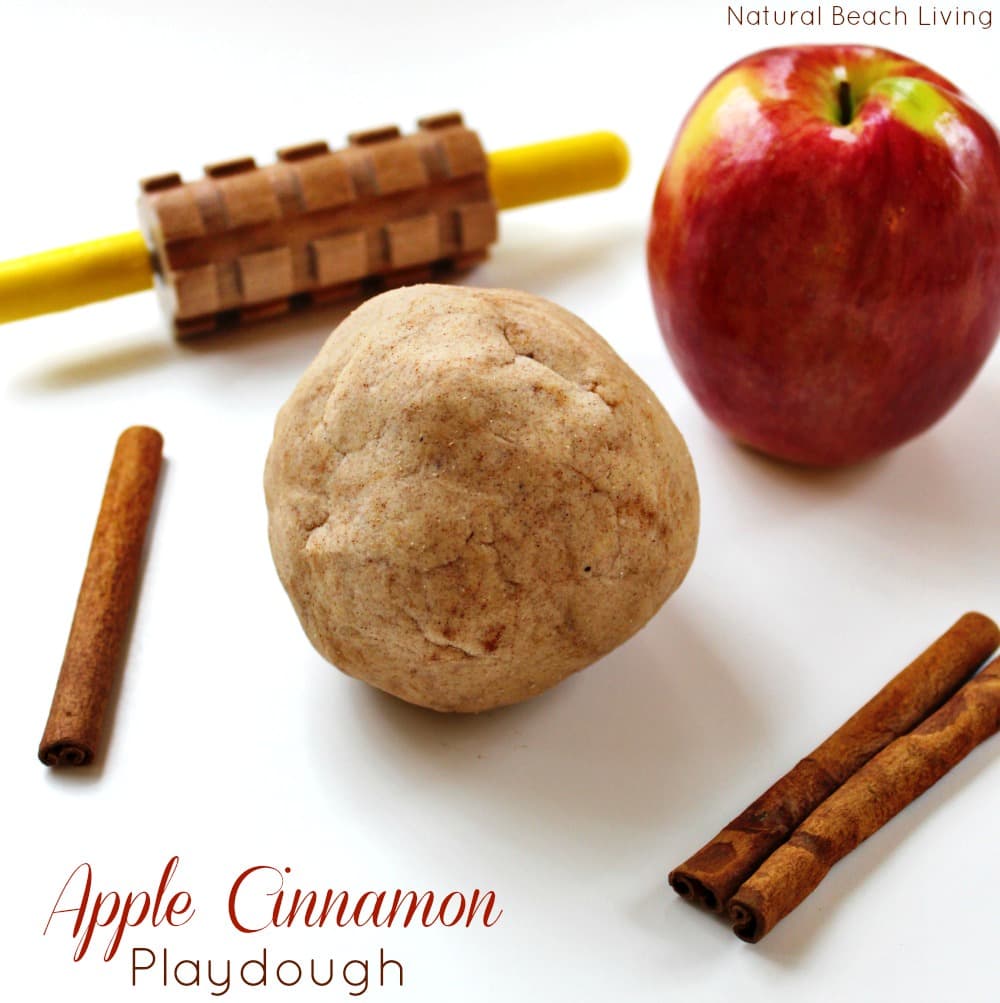Ball of brown play dough surrounded by cinnamon sticks and an apple.