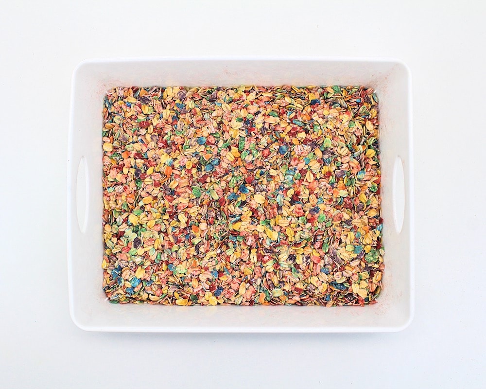 White container filled with rainbow dyed oats (all colours mixed together)