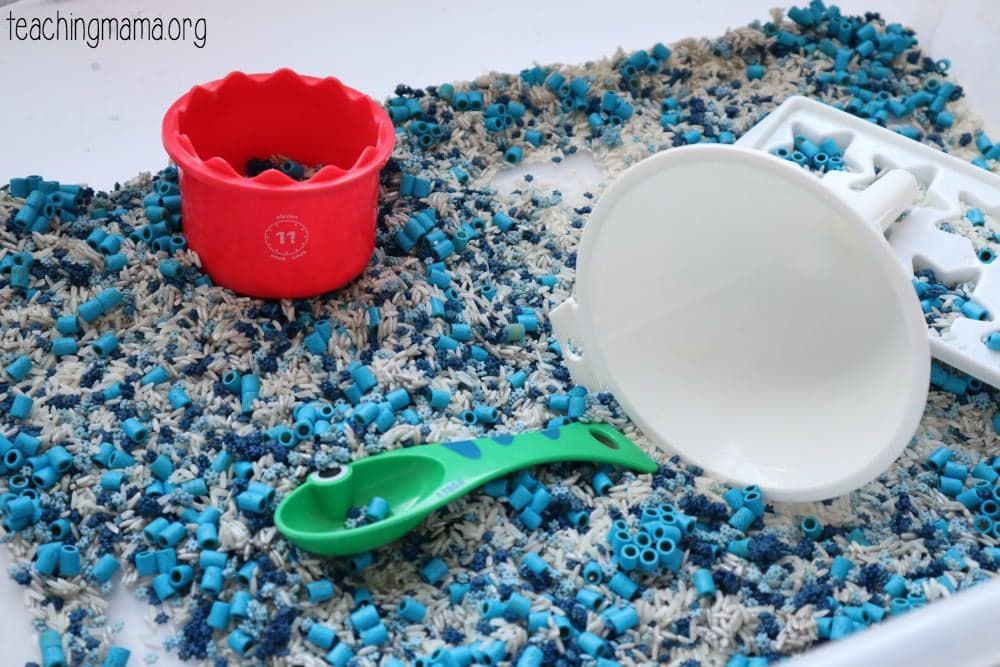 Sensory bin containing rice and pasta that have been dyed blue.