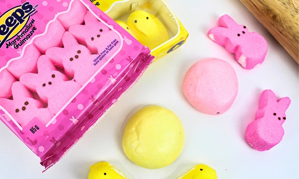 Balls of pink and yellow play dough surrounded by bunny and chick marshmallow Peeps.