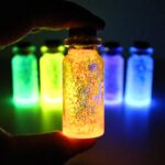 Hand holding up a glowing jar, in front of other glowing jars.
