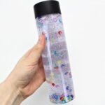 Hand holding a sensory bottle with small beads.