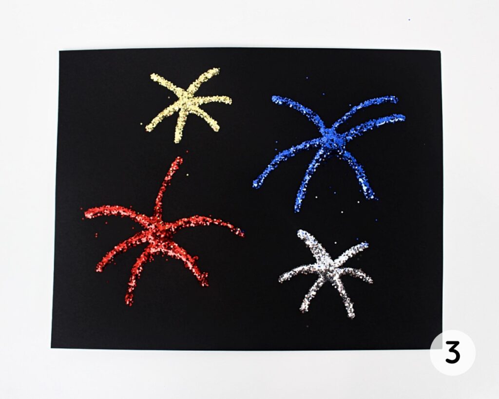 Firework shapes on black paper, covered with glitter, excess removed.