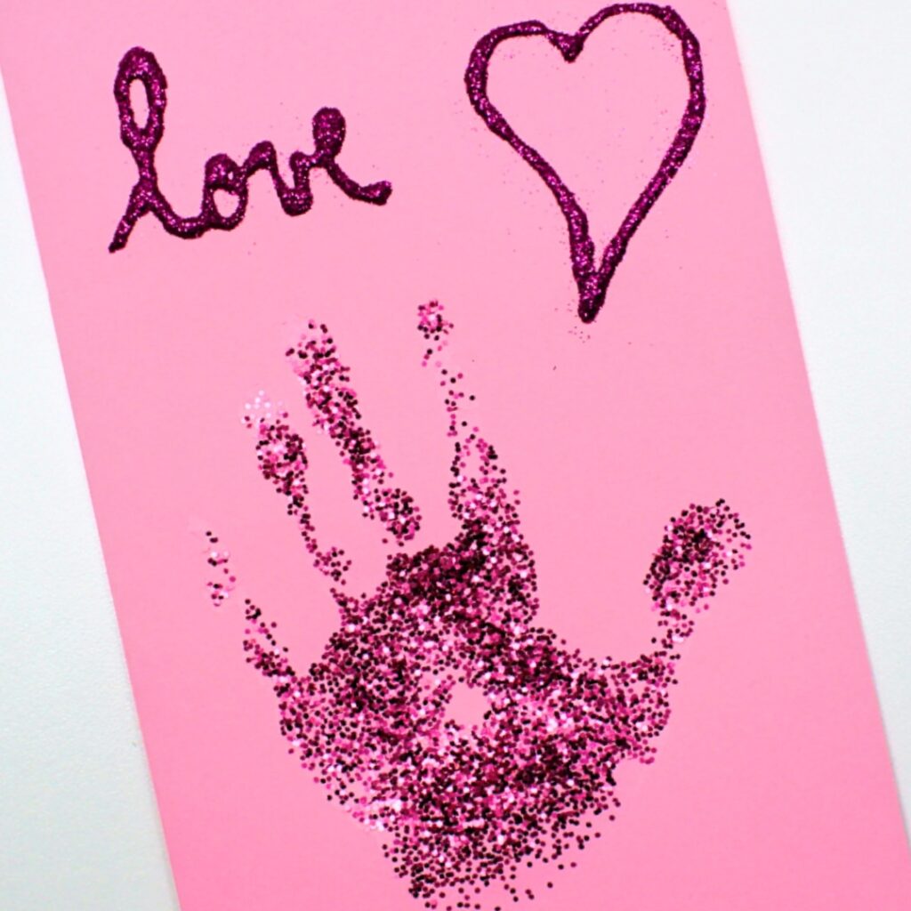Pink card with glittery handprint.
