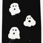 White blow painted ghosts on black cardstock.