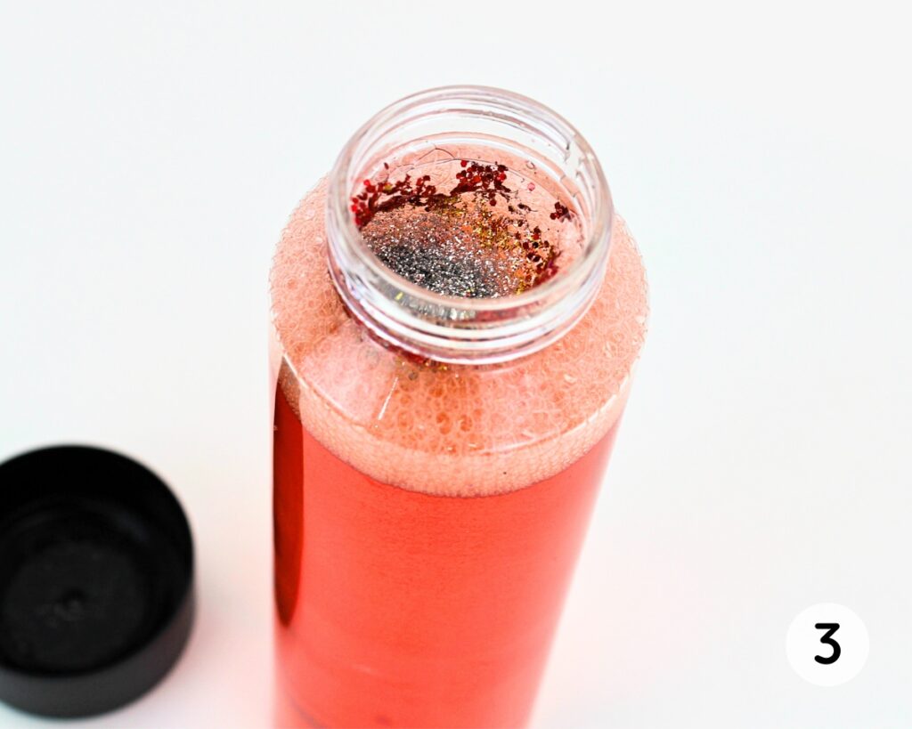Bottle with red liquid and glitter.