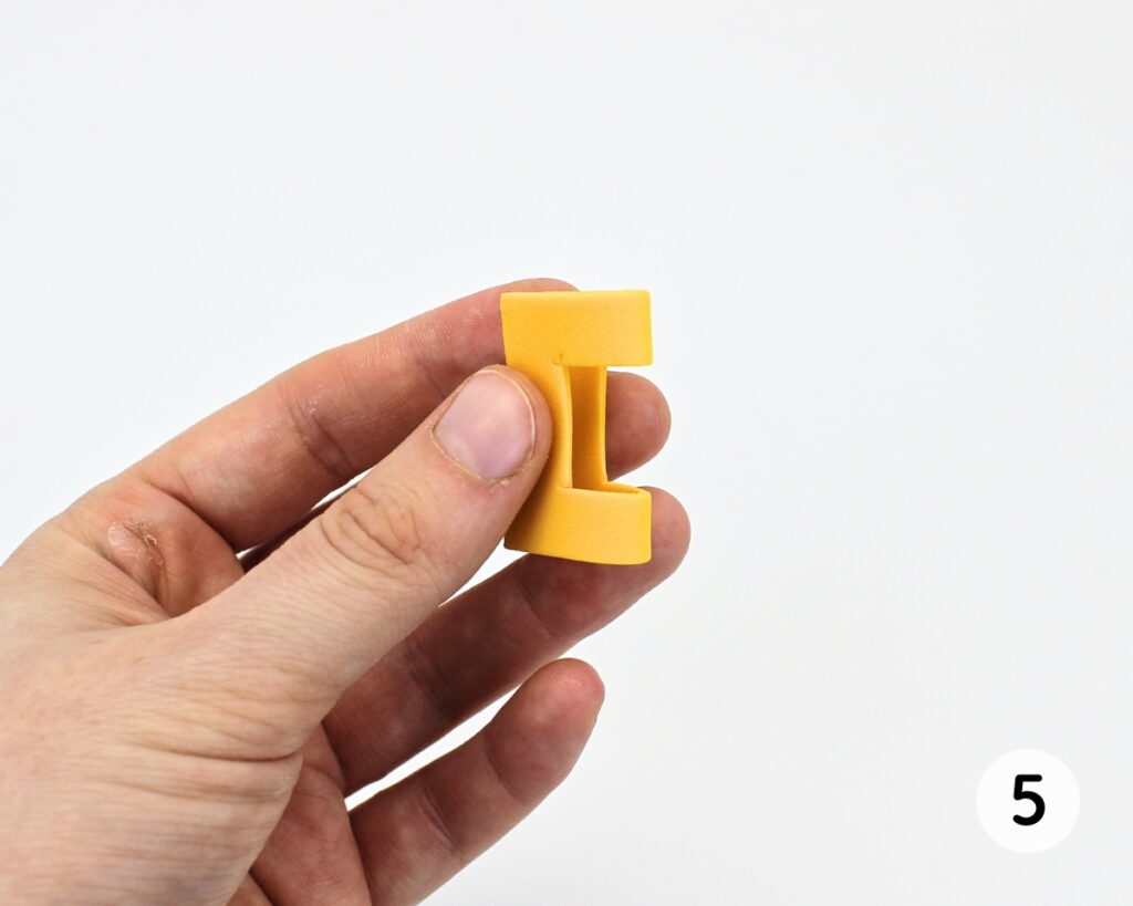 Hand holding up folded yellow foam belt buckle.