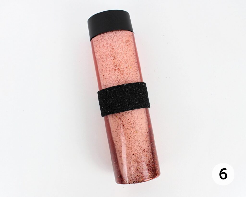 Red glitter bottle with black foam wrapped around the middle.