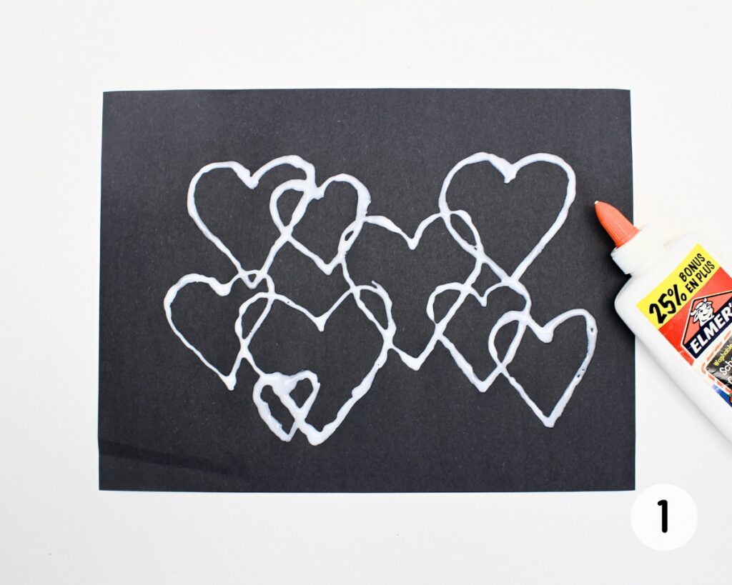 Overlapping hearts traced on black paper using white liquid glue.