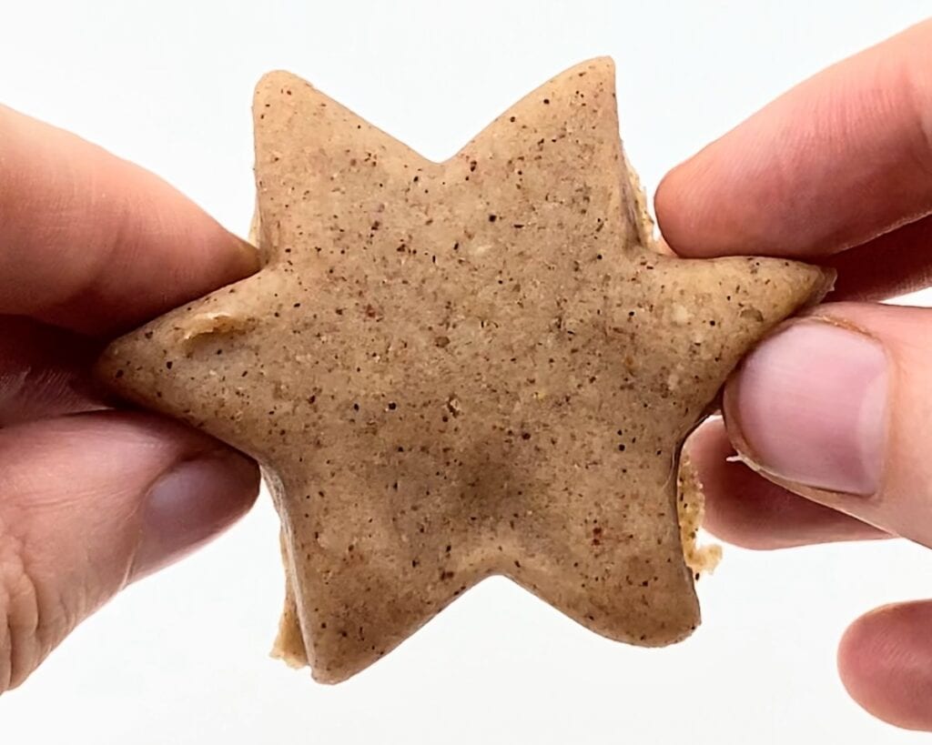 Hands holding up a star-shaped piece of cinnamon-vanilla play dough.