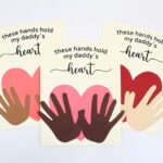 3 crafts of hands holding a heart, with different hand and heart colors.