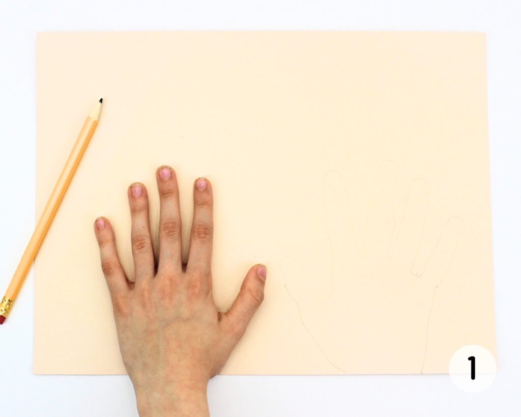 Child's hand pressed down on beige cardstock.