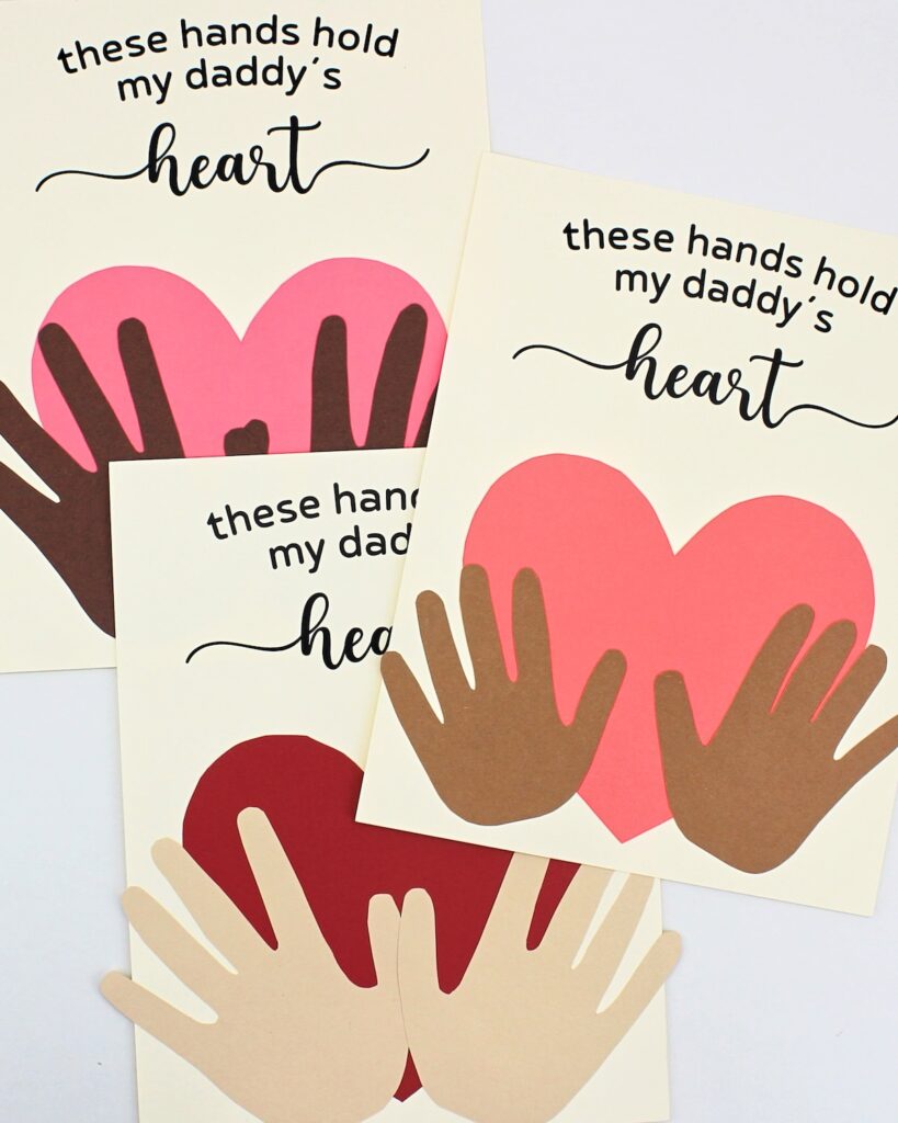 3 crafts of hands holding a heart, with different hand and heart colors.