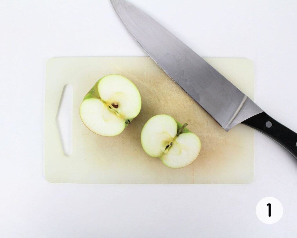 Apple sliced in half with a big knife.