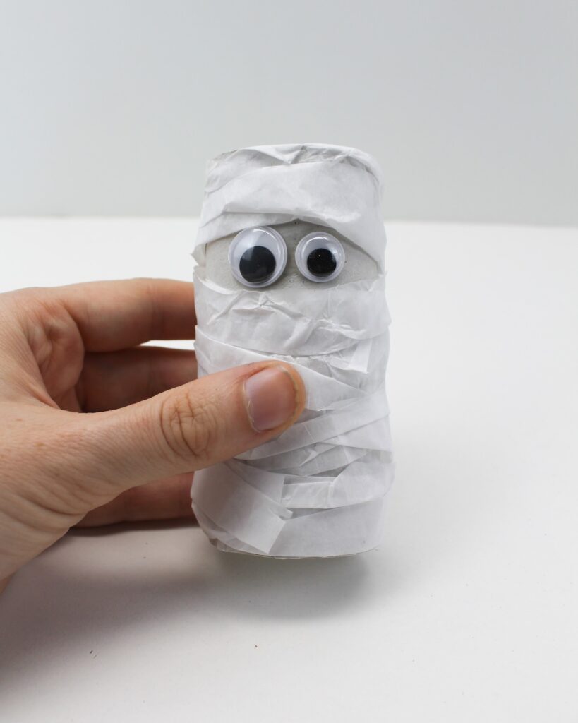 Hand holding finished paper roll mummy craft.