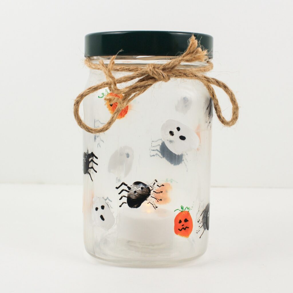 Glass jar candle holder with fingerprint ghosts, spiders and jack-o'-lanterns.