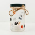 Glass jar candle holder with fingerprint ghosts, spiders and jack-o'-lanterns.